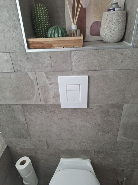 Witte Grohe bedieningsplaat strak in het tegelwerk