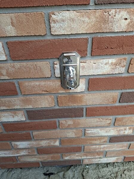 Chromen buitenkraan met wandplaat gemonteerd op een bakstenen gevel