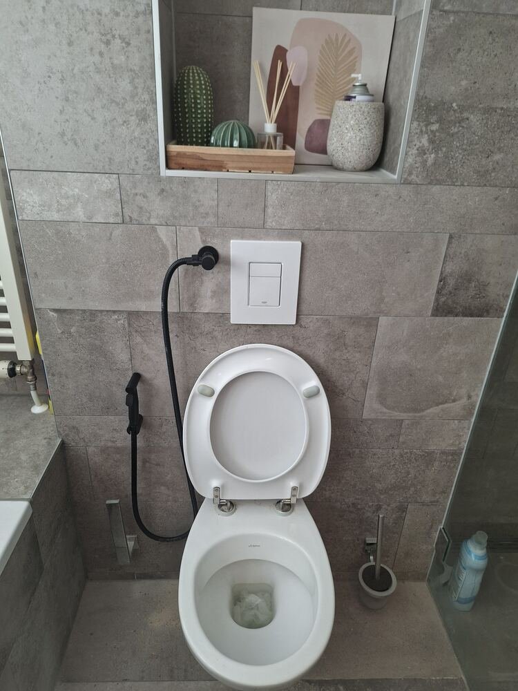 Zwarte bidetsproeier netjes aangesloten naast een hangtoilet