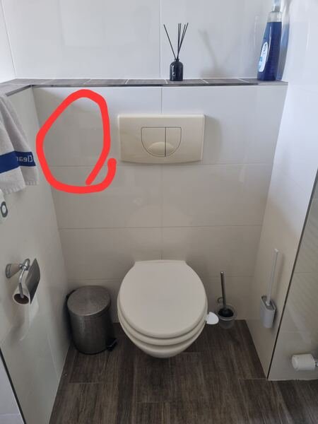Toilet vóór montage, met de gewenste plek voor de bidetsproeier aangegeven op de wand